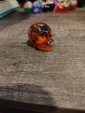 Amber orange and black swirl mini resin skull - side view