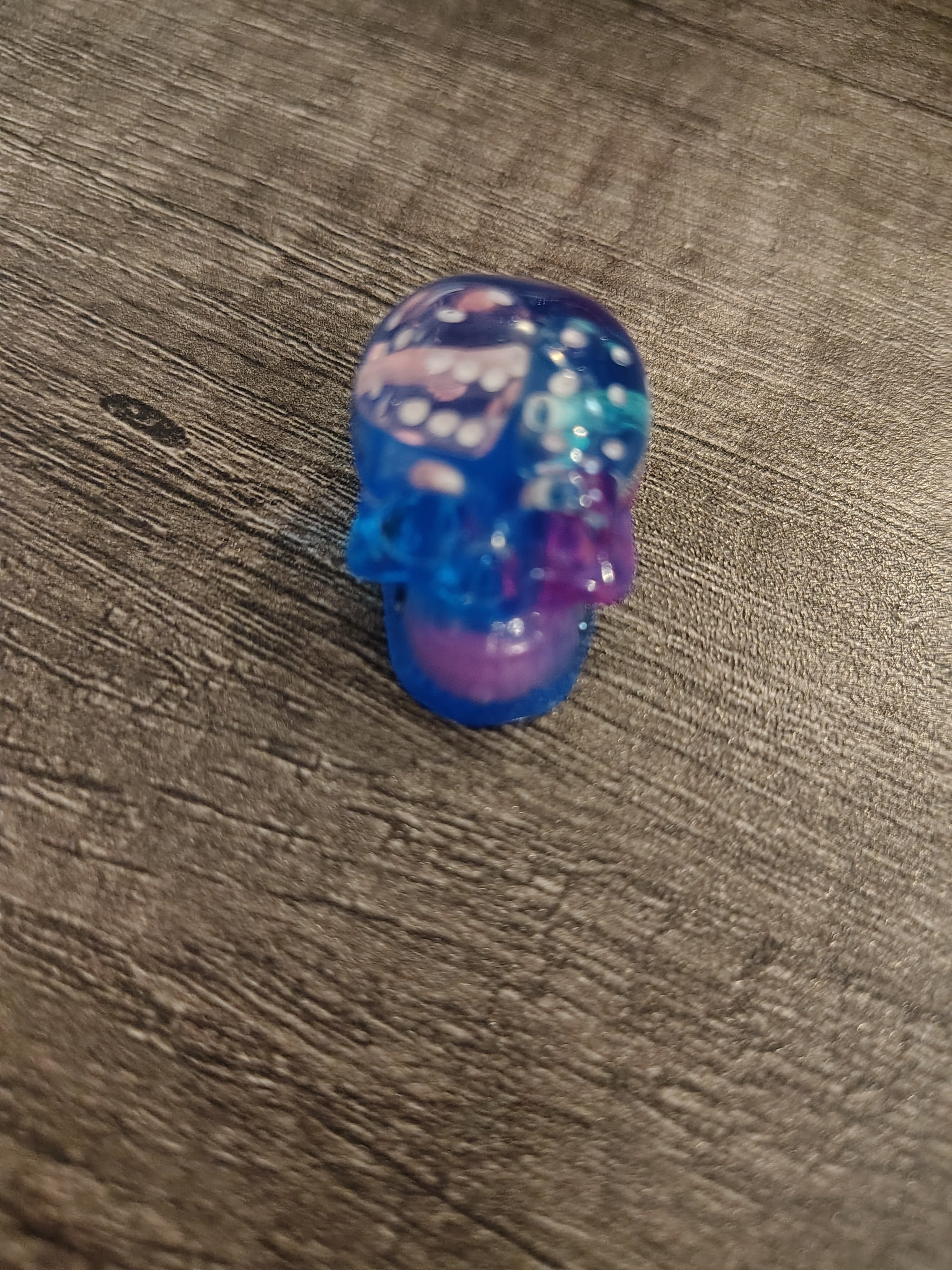 Clear blue and purple resin mini skull with white d6 dice - side view