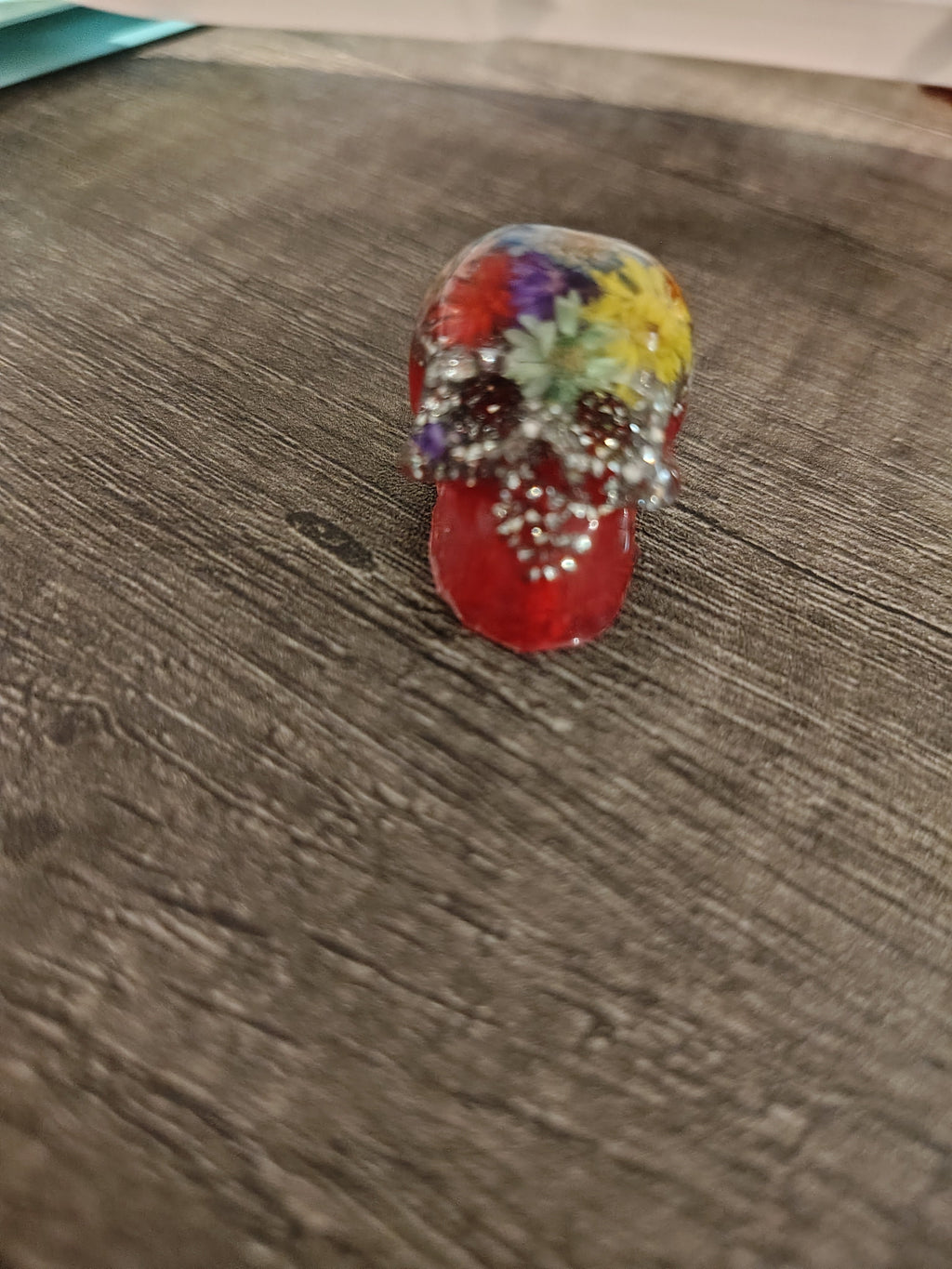 Red resin mini skull with real pressed flowers and silver crushed glitter - front view