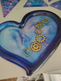 Heart-shaped blue and purple swirl resin tray with bronze steampunk gears and navy rim