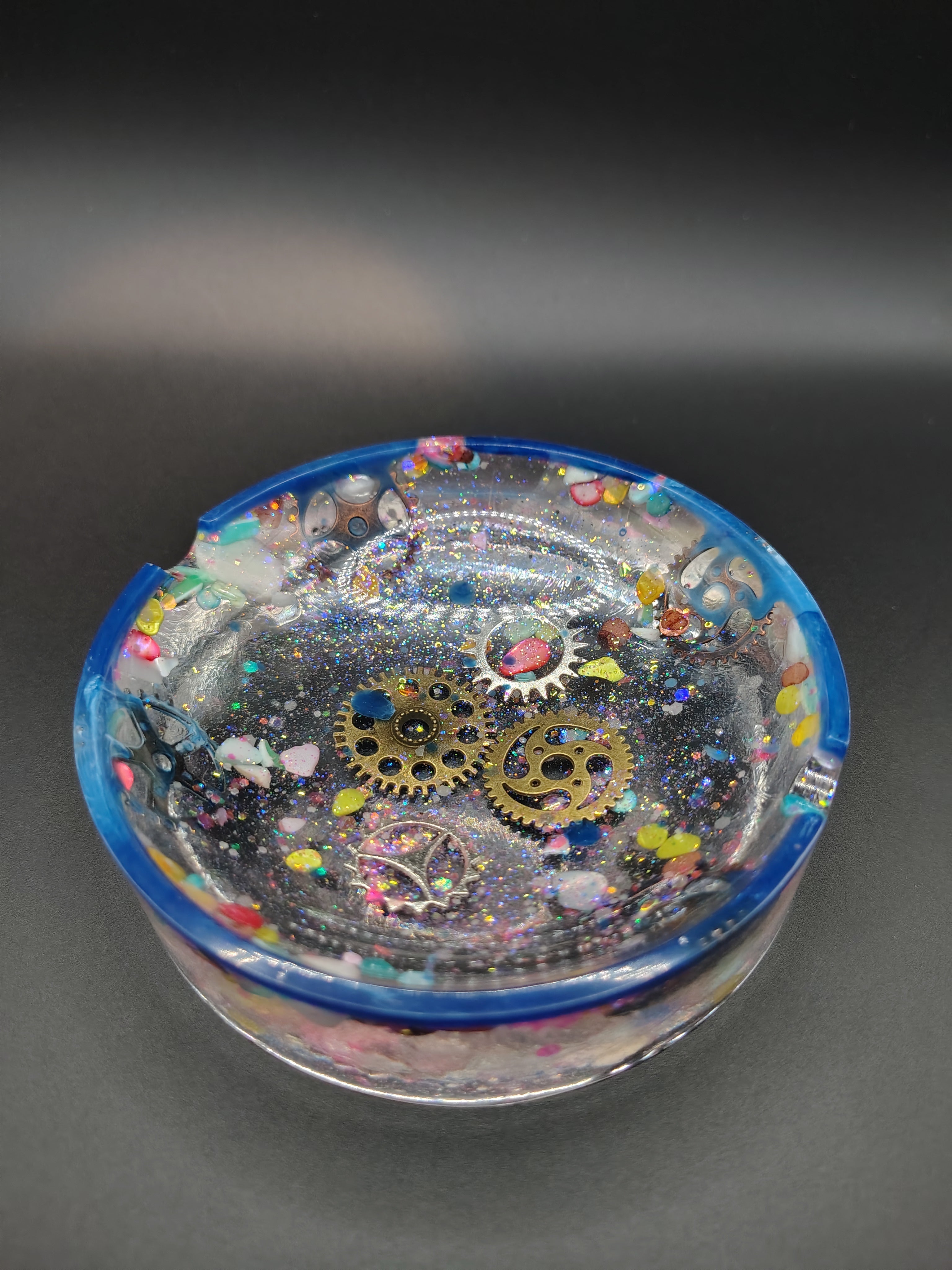 Round resin ashtray with bronze steampunk gears, holographic glitter, and blue rim