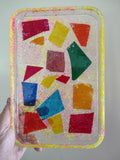 Geometric stained glass shards embedded in clear resin tray with Loomlight glow-in-the-dark glitter
