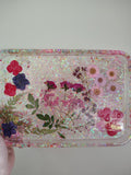 Pressed flowers and botanicals in pink glitter resin tray with Loomlight glow-in-the-dark glitter