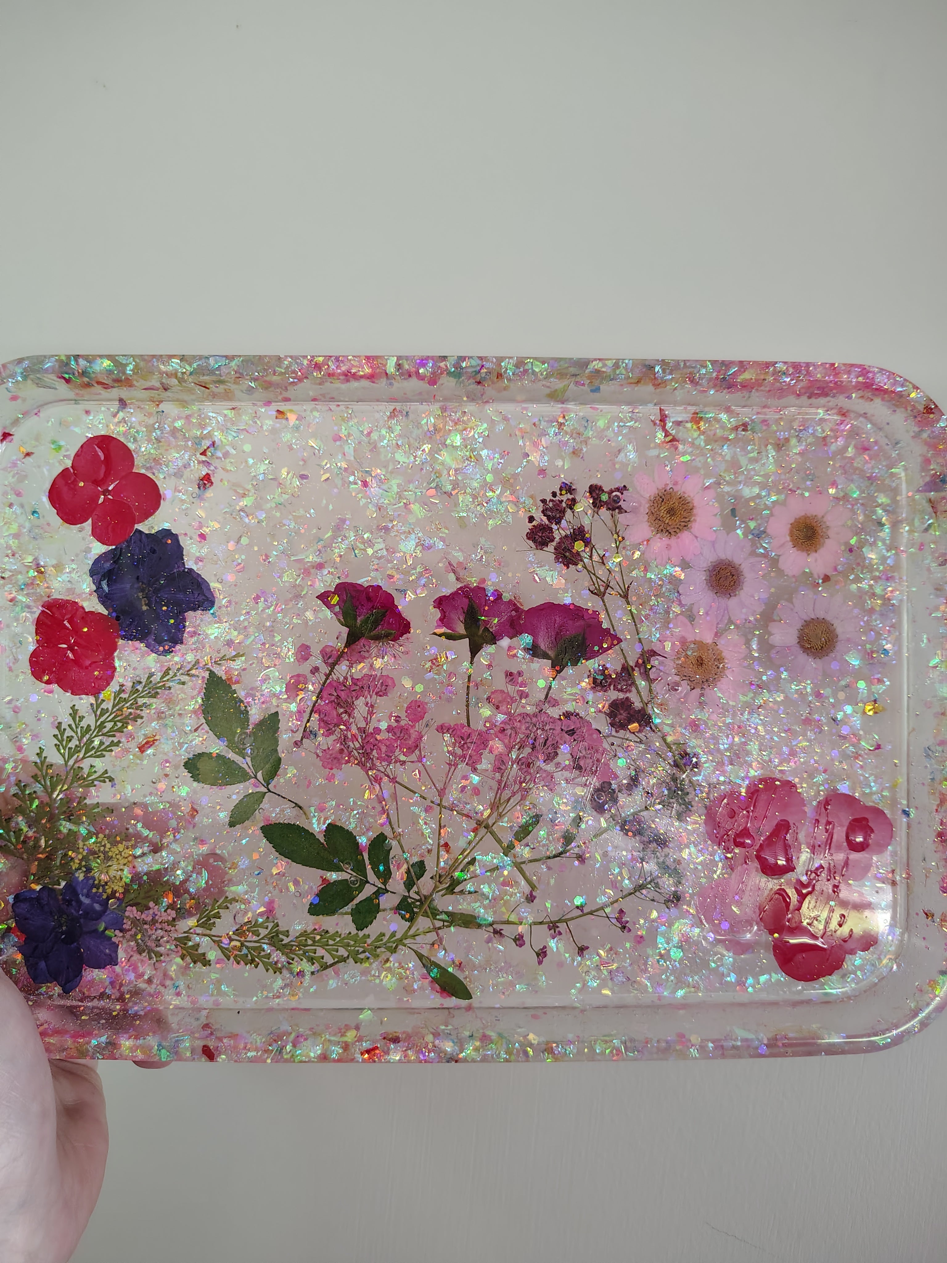 Pressed flowers and botanicals in pink glitter resin tray with Loomlight glow-in-the-dark glitter